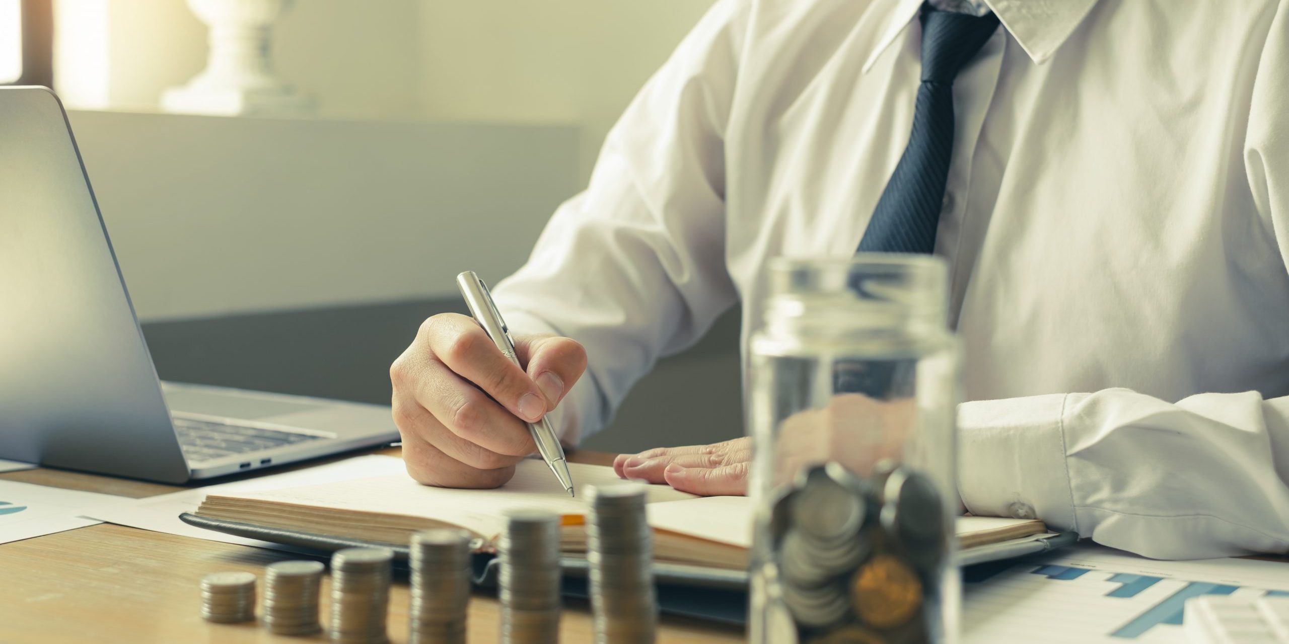 Man’s is calculating financial graphs with coins to save money,
