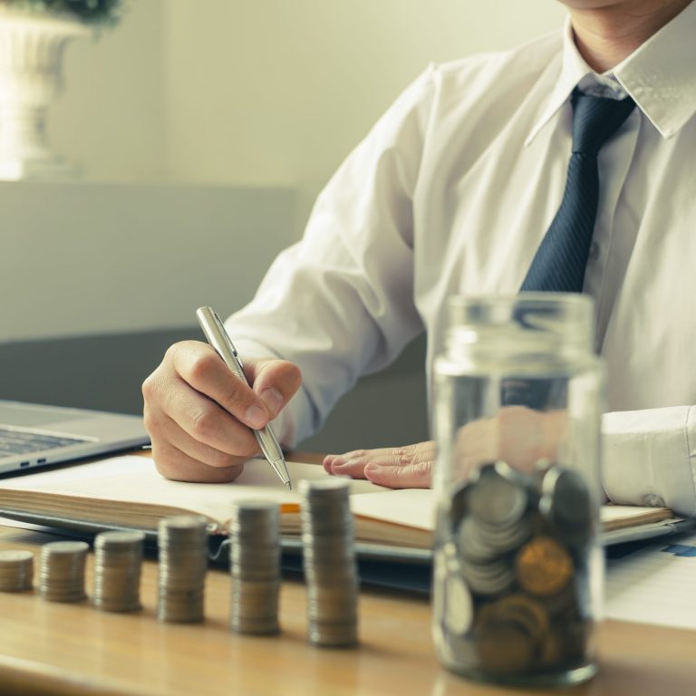 Man’s is calculating financial graphs with coins to save money,